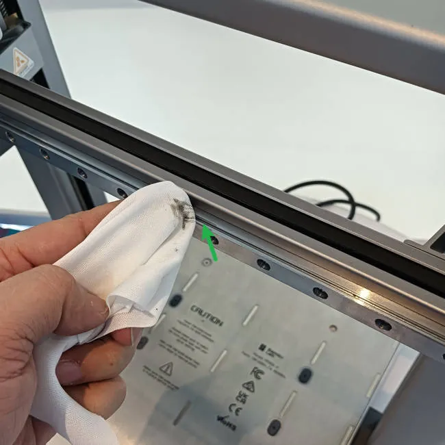 Limpeza da guia do eixo de impressora 3D com pano antes do transporte
